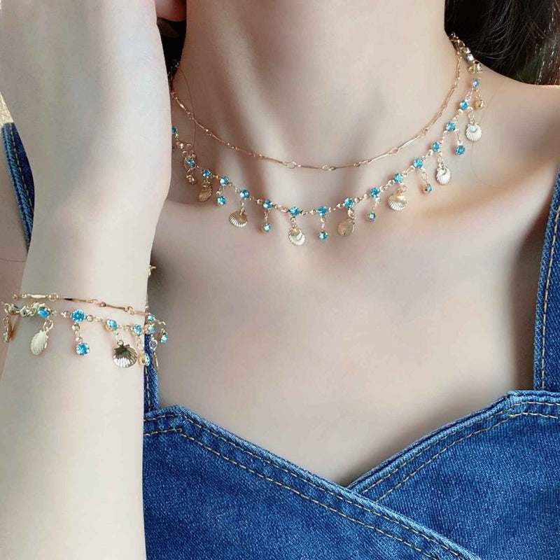 Ariana – Gold necklace with shells & blue crystals in boho beach style