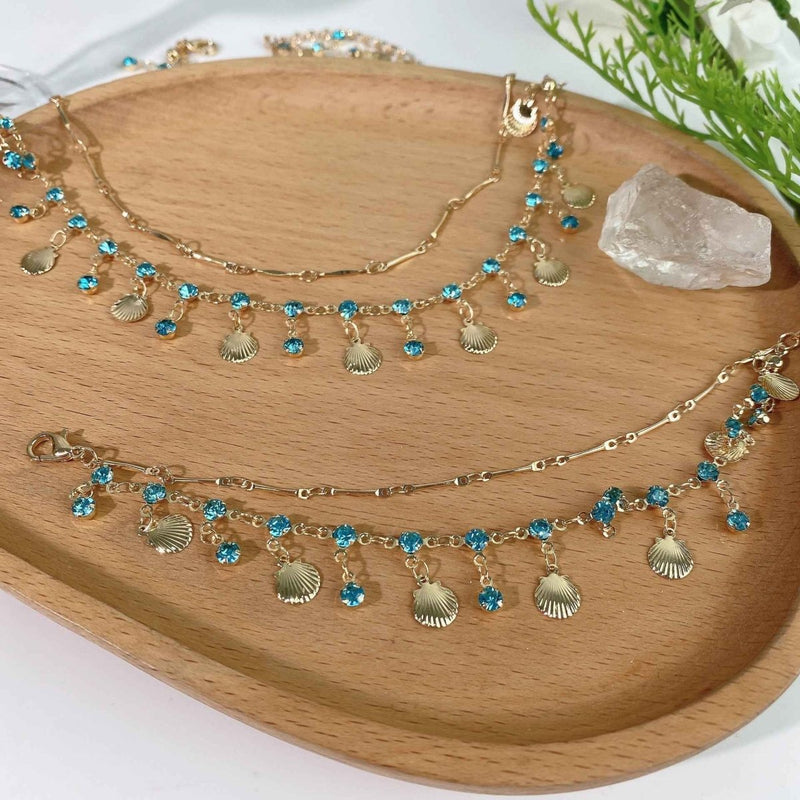 Ariana – Gold necklace with shells & blue crystals in boho beach style