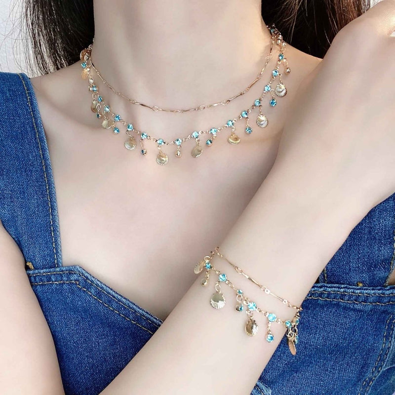 Ariana – Gold necklace with shells & blue crystals in boho beach style